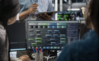 Close up of data center programmers using PC to visualize artificial intelligence neural networks. Server farm IT experts looking at monitor, working together to oversee AI systems