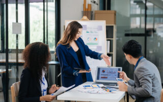 Group of young Asian business people discussing business plan at modern startup in creative business discussing work modern office building